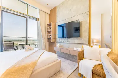 a bedroom with a bed and a tv and a couch at Studio Near Meydan Golf Club, 15-Minute Drive to Dubai Mall, Burj Khalifa and Downtown Attractions, Azizi Riviera 46, Al Merkadh by Deluxe Holiday Homes in Dubai