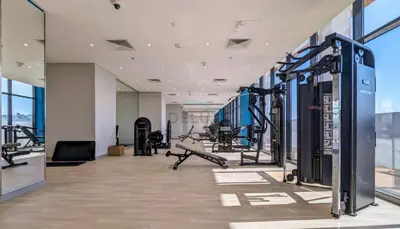a gym with cardio equipment in a building at Studio Near Meydan Golf Club, 15-Minute Drive to Dubai Mall, Burj Khalifa and Downtown Attractions, Azizi Riviera 46, Al Merkadh by Deluxe Holiday Homes in Dubai