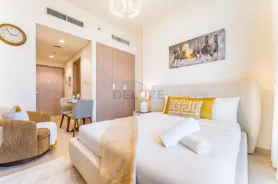 a bedroom with a white bed and a couch at Studio Near Meydan Golf Club, 15-Minute Drive to Dubai Mall, Burj Khalifa and Downtown Attractions, Azizi Riviera 46, Al Merkadh by Deluxe Holiday Homes in Dubai