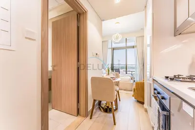 a kitchen with a table and a chair in a room at Studio Near Meydan Golf Club, 15-Minute Drive to Dubai Mall, Burj Khalifa and Downtown Attractions, Azizi Riviera 46, Al Merkadh by Deluxe Holiday Homes in Dubai