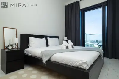 a bedroom with a bed and a large window at Mira Holiday Homes - Luxury, Stylish & Cozy Studio in Downtown Jebel Ali in Dubai