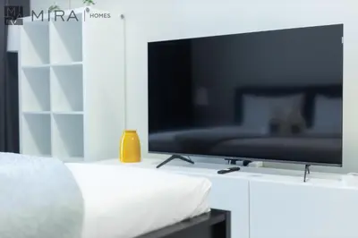 a flat screen tv sitting on top of a white table at Mira Holiday Homes - Luxury, Stylish & Cozy Studio in Downtown Jebel Ali in Dubai