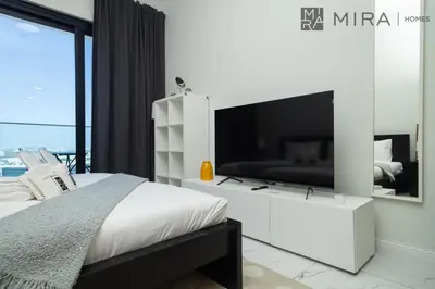 a bedroom with a large television on a white cabinet at Mira Holiday Homes - Luxury, Stylish & Cozy Studio in Downtown Jebel Ali in Dubai