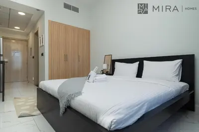 a bedroom with a large bed with white sheets at Mira Holiday Homes - Luxury, Stylish & Cozy Studio in Downtown Jebel Ali in Dubai