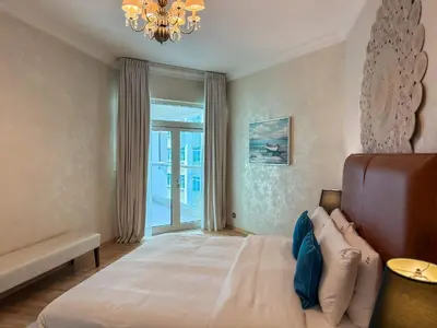 a bedroom with a large bed and a chandelier at Sea View Beachfront 3BR Apartment - Shoreline 6 in Dubai