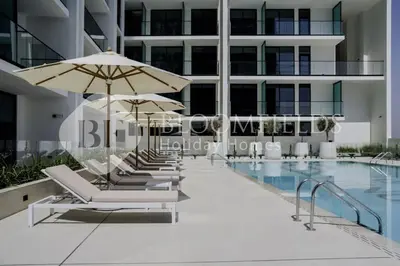 a row of chairs and umbrellas next to a swimming pool at Bloomfields Cozy Stu Binghatti Azure in Dubai