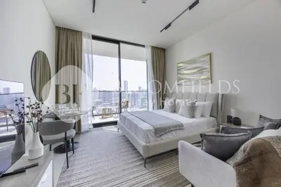 a bedroom with a king sized bed and a living room at Bloomfields Cozy Stu Binghatti Azure in Dubai