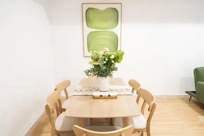 a dining room table with a vase of flowers on it at Boho Style 2BHK Apartment With Sea View Next to Tram Station in Dubai