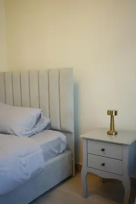 a bed and a nightstand with a lamp on it at RIVIERA HOME ESCAPE 2BHK pool Gym in Dubai