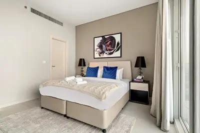 a bedroom with a large white bed with blue pillows at Spacious 1BR with Huge Terrace in Dubai