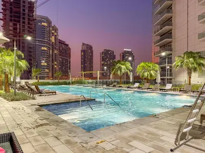 a swimming pool with palm trees and buildings at Spacious 1BR with Huge Terrace in Dubai