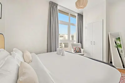 a white bedroom with a large white bed and a window at FIRST CLASS VILLA Modern Comfort & Style in Dubai