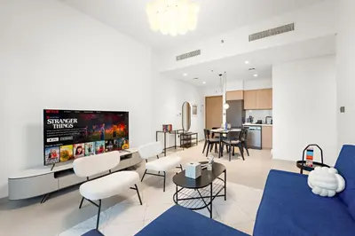 a living room with a blue couch and white chairs at Spacious 1BR in Downtown with Balcony & Pool in Dubai