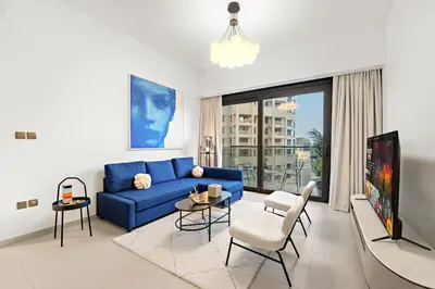 a living room with a blue couch and a tv at Spacious 1BR in Downtown with Balcony & Pool in Dubai