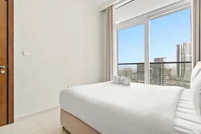 a bedroom with a white bed and a large window at FIRST CLASS 1BR Canal View Escape in Dubai