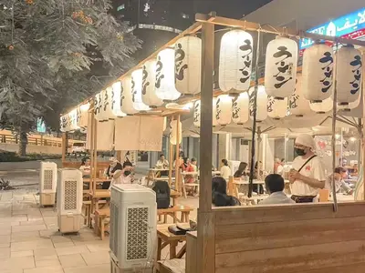a restaurant with people sitting at tables in a street at Cosmos Living Delightful Studio in Dubai