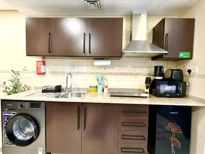 a kitchen with a sink and a washing machine at Cosmos Living Delightful Studio in Dubai