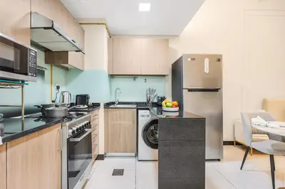 a kitchen with a stainless steel refrigerator and a dishwasher at FIRST CLASS Studio Stylish & Cozy JVC Escape in Dubai
