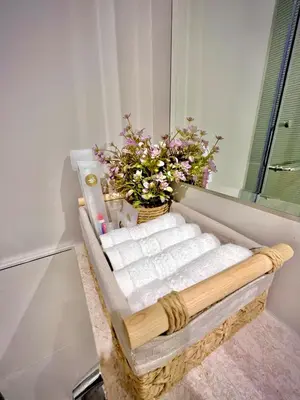 a bathroom with towels and a basket of flowers at Cosy flat in the heart of Dubai in Dubai