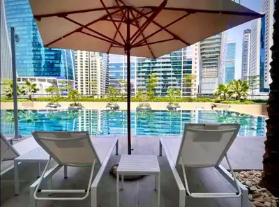 a table and chairs with an umbrella and a pool at Cosy flat in the heart of Dubai in Dubai