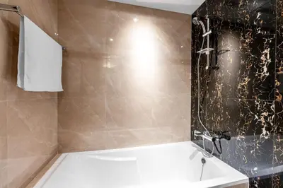 a bathroom with a white tub and a shower at Chic Studio Near Burj Khalifa in Dubai