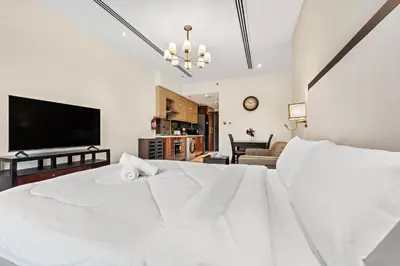 a bedroom with a white bed and a flat screen tv at Chic Studio Near Burj Khalifa in Dubai