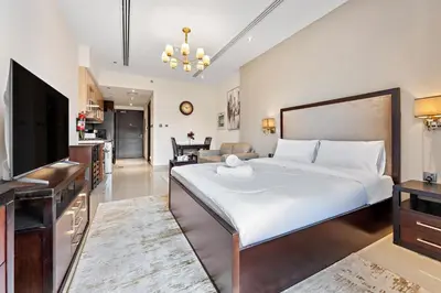 a bedroom with a large bed and a living room at Chic Studio Near Burj Khalifa in Dubai