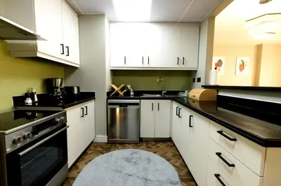 a kitchen with white cabinets and a sink and a rug at Full Sea View Luxury Large 1 BR in JBR in Dubai