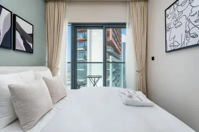 a bedroom with a white bed and a large window at Gala Guests - Golf Gate Residences with Panoramic Golf Views in Dubai