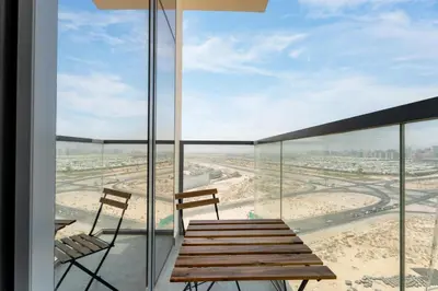 a balcony with a wooden bench and two chairs at Gala Guests - Golf Gate Residences with Panoramic Golf Views in Dubai