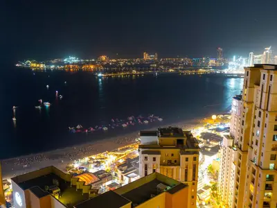 a view of a city at night with the ocean at Beachfront 2BR Dubai Eye & Sea View Beach Access in Dubai