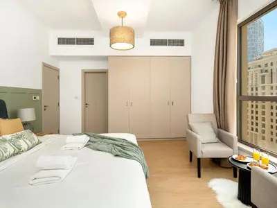 a bedroom with a large white bed and a chair at Beachfront 2BR Dubai Eye & Sea View Beach Access in Dubai