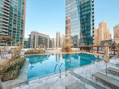 a large swimming pool in a city with tall buildings at Dubai Marina Skyline with Sunset and Sunrise View in Dubai