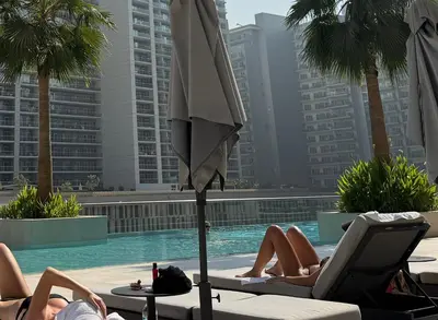 a group of people laying around a swimming pool with an umbrella at The Sterling 4 sleep with AC parking and pool in Dubai