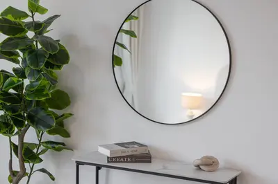 a mirror on a wall next to a table with a plant at Sanctuary Stays - Premium 1BR - Burj Khalifa Views - Near Dubai Mall in Dubai