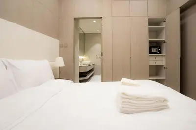 a bedroom with a white bed and a bathroom at Designer 1BR Apt with Modern and Airy Layout in Dubai