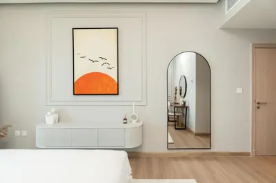 a white bedroom with a bed and a mirror at Luxury Renovated 1BR w Full Sea View in Dubai