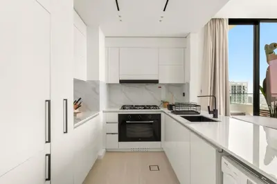 a white kitchen with a stove and a sink at VayK - Modern 2BD Retreat with Private Pool in JVC in Dubai
