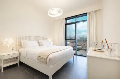 a white bedroom with a bed and a large window at Luxury 2BR 34th Floor Burj Khalifa Sea Creek View in Dubai