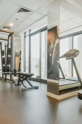 a gym with treadmills and a wall with mirrors at Work & Relax Above the City- JVC Perfect Stay in Dubai