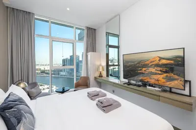 a bedroom with a large white bed and a large window at Cozy Waterfront Studio Pool, Gym, Parking in Dubai
