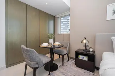 a room with a table and two chairs and a bed at Cozy Waterfront Studio Pool, Gym, Parking in Dubai