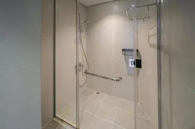 a shower with a glass door in a bathroom at Cozy Waterfront Studio Pool, Gym, Parking in Dubai