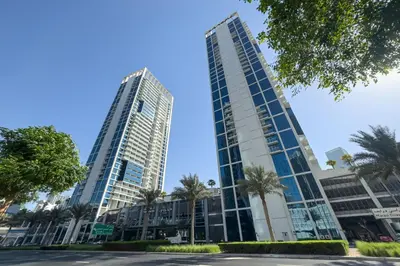 two tall buildings in a city with palm trees at Cozy Waterfront Studio Pool, Gym, Parking in Dubai
