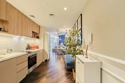 a kitchen with white cabinets and a dining room at FAM Living Contemporary 1BR Apartment Urban Oasis in Dubai