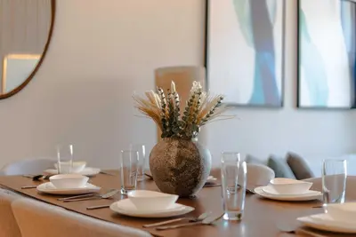 a dining room table with a vase of flowers on it at TRPS - Imperial Avenue, Downtown - Burj Khalifa View, Brand New, Amazing Facilities in Dubai