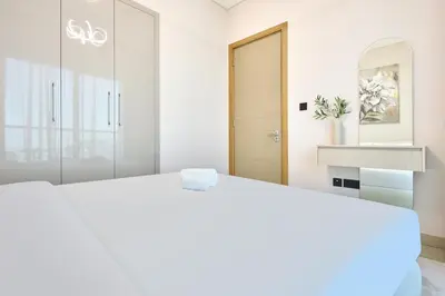 a white bedroom with a large bed and a mirror at STAY BY LATINEM Luxury 1BR Holiday Home W 2809 Near Burj Khalifa in Dubai