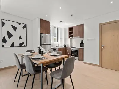 a kitchen and dining room with a wooden table and chairs at Coastal Haven 1BDR in La Cote B4-12 in Dubai