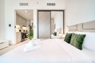 a bedroom with a large white bed with two towels at Bright Studio in Binghatti Canal in Dubai