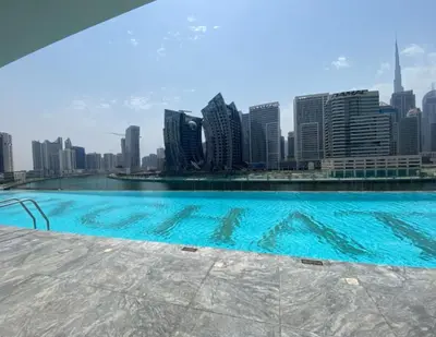 a swimming pool with a city skyline in the background at Bright Studio in Binghatti Canal in Dubai